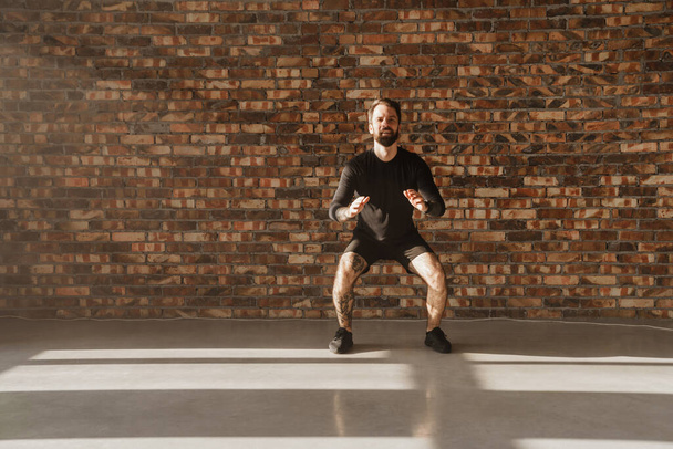 Confiado deportista blanco de mediana edad haciendo ejercicio en una habitación luminosa saltando - Foto, Imagen