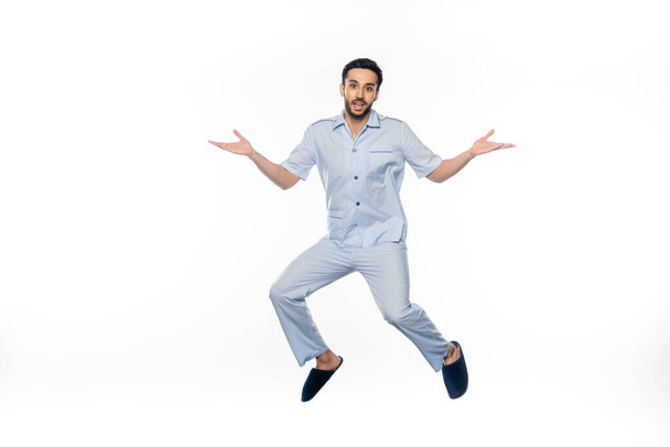 hombre barbudo en pijama levitando mientras gesticulaba en blanco  - Foto, imagen