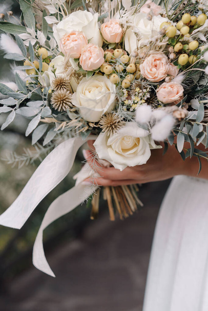Bride in a wedding dress holding a wedding bouquet in her hands - Fotoğraf, Görsel