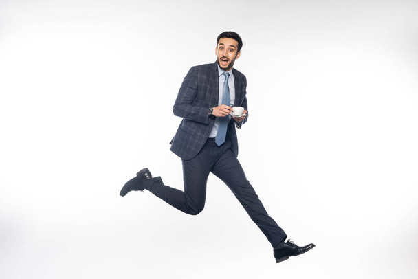 excited businessman in suit jumping with cup of coffee on white  - Photo, Image