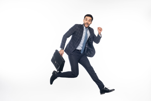 hombre de negocios positivo en traje saltando con maletín en blanco  - Foto, Imagen