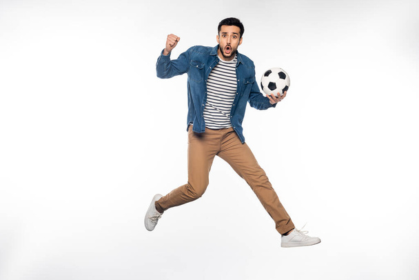 worried man levitating while holding soccer ball and cheering on white  - Valokuva, kuva