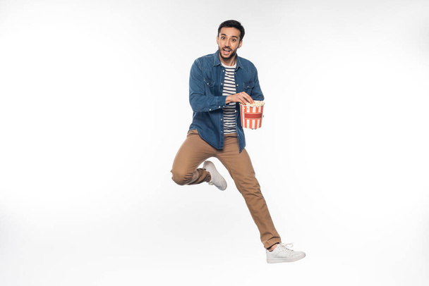 glücklicher Mann schwebt, während er Popcorn-Eimer auf weiß hält - Foto, Bild