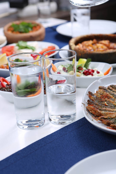 Traditioneller türkischer und griechischer Esstisch mit einem speziellen Alkoholgetränk Raki. Ouzo und türkischer Raki ist ein mit trockenem Anis aromatisierter Aperitif, der in der Türkei, Griechenland, Zypern und im Libanon weit verbreitet ist. - Foto, Bild