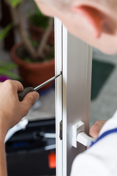 Handyman repairing window with screwdriver - Foto, afbeelding