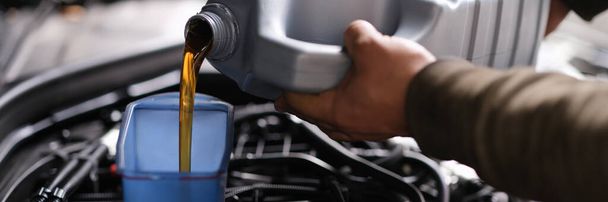 Locksmith mechanic pours engine oil into plastic container on motor engine - Foto, immagini