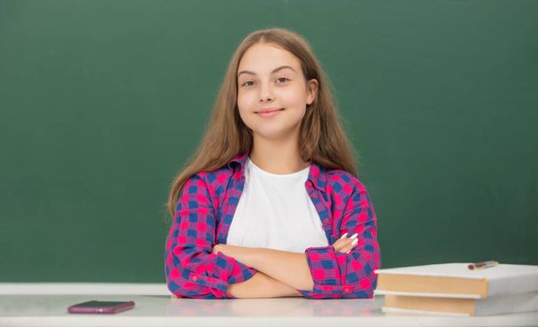 vrolijk kind zit in klas op schoolbord, september - Foto, afbeelding