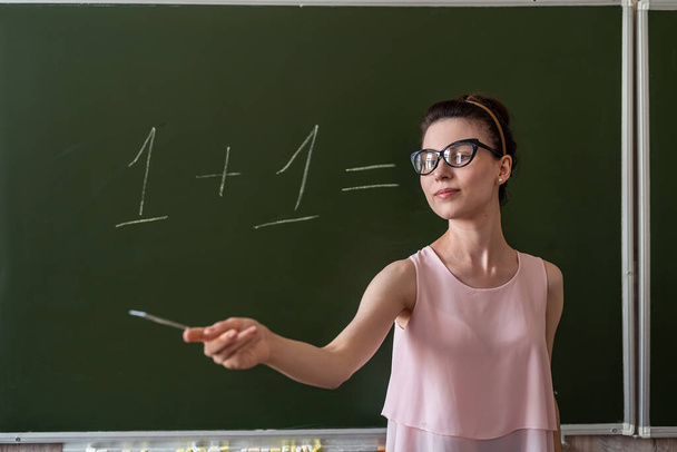 young primary female teacher written on chalkboard one plus one, education concept - Photo, Image