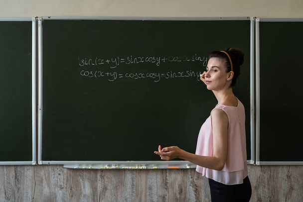 Nainen opettaja kirjoittaa matematiikan kaavoja, cos ja syntiä. koulutuksen käsite - Valokuva, kuva