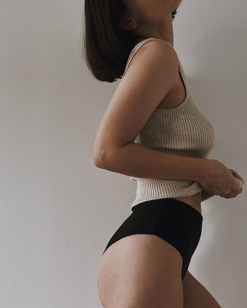 Pretty sexy young woman in neutral beige tee and black panties on white background. Aesthetic elegant fashion vogue composition - Zdjęcie, obraz