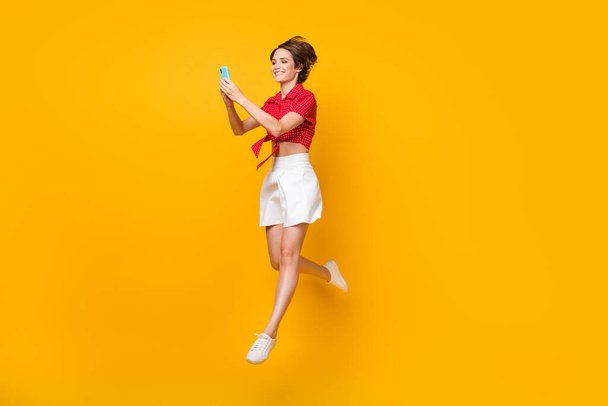 Full length profile photo of attractive cheerful lady beaming smile typing blog post isolated on yellow color background - 写真・画像