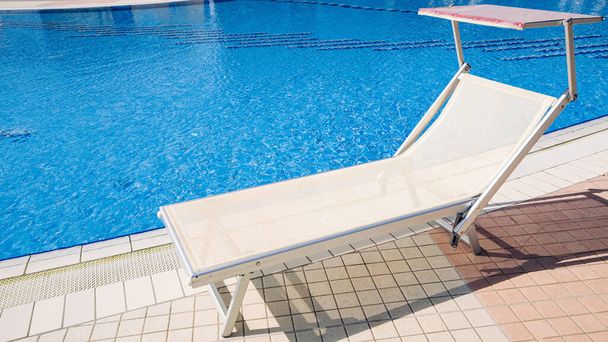 Basen wypoczynkowy. Krzesło letniskowe, relaks w luksusowym hotelowym basenie. Łóżko plażowe. Wakacyjne leżaki. Niebieska woda, słoneczny szczęśliwy wypoczynek - Zdjęcie, obraz