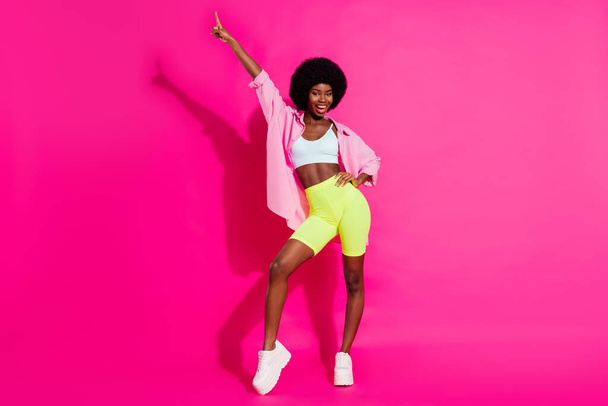 Photo of funny sweet dark skin woman dressed crop top smiling dancing pointing finger isolated pink color background - Foto, Bild