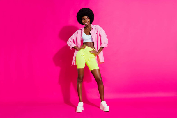 Photo of charming sweet dark skin lady wear casual shirt dancing looking empty space smiling isolated pink color background - Valokuva, kuva