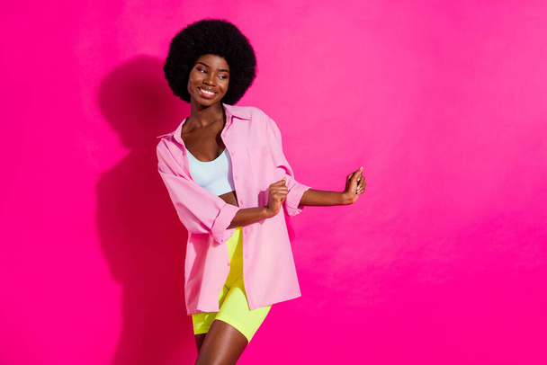 Photo of sweet cute dark skin lady wear casual shirt dancing looking empty space smiling isolated pink color background - Photo, Image