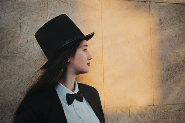 retro portrait in profile of a young girl in a top hat and bow tie - Foto, Imagen