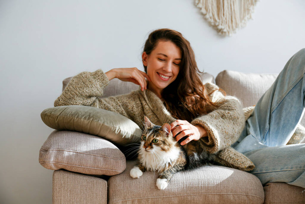 Portrait of young woman holding cute siberian cat with green eyes. Female hugging her cute long hair kitty. Background, copy space, close up. Adorable domestic pet concept. - Φωτογραφία, εικόνα