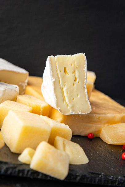 τυρί πιάτο διάφορα είδη τυρί μπρι, καμαμπέρ, παρμεζάνα, τσένταρ και άλλα υγιεινά σνακ διατροφής γεύμα στο τραπέζι αντίγραφο χώρο τροφίμων ρουστίκ φόντο. πάνω όψη - Φωτογραφία, εικόνα