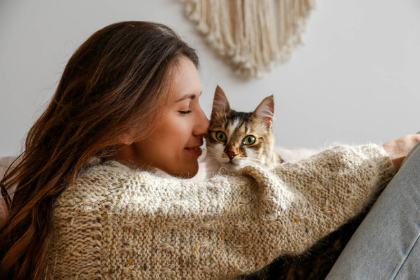 Portrait of young woman holding cute siberian cat with green eyes. Female hugging her cute long hair kitty. Background, copy space, close up. Adorable domestic pet concept. - Фото, зображення