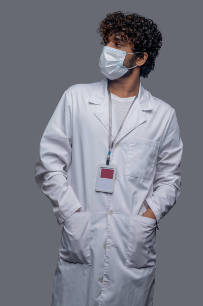 Healthcare professional dressed in a lab coat staring away - Fotó, kép