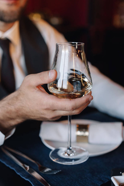 Glass with wine in the hand of the groom in a wedding suit - Photo, image