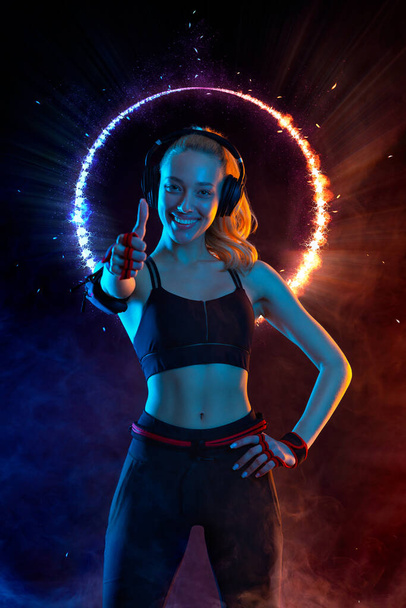 Strong athletic fit woman on black with neon lights background wearing in the sportswear. Fitness and sport motivation. - Zdjęcie, obraz