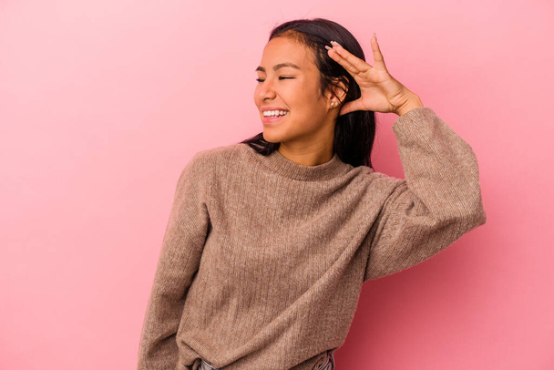Young latin woman isolated on pink background  trying to listening a gossip. - Foto, Imagem