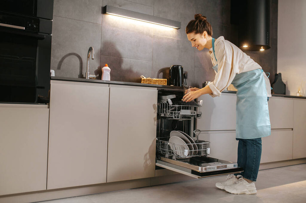 Young woman in the kitchen looking busy while washing the plates - Foto, Bild