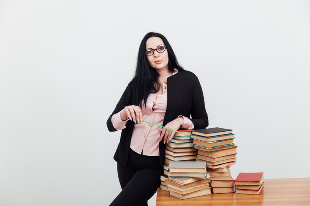 Μια μελαχρινή γυναίκα σε μια δασκάλα με πολλά βιβλία. - Φωτογραφία, εικόνα