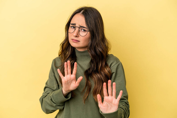 Young caucasian woman isolated on yellow background rejecting someone showing a gesture of disgust. - Photo, Image
