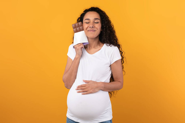 Смішна вагітна латинська леді Holding і huging шоколад на студії
 - Фото, зображення