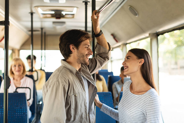 Joyeux jeune couple debout dans le bus et parler - Photo, image