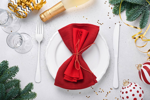 Christmas table setting white color with silverware, napkin red color, Christmas balls, champagne, glasses on white background for xmas greetings. Mock up. - Photo, image