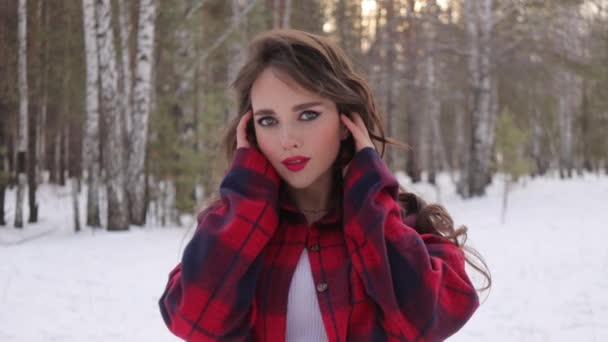 波状の髪立ちと冬の森の中で顔に触れる若い女性 - 映像、動画