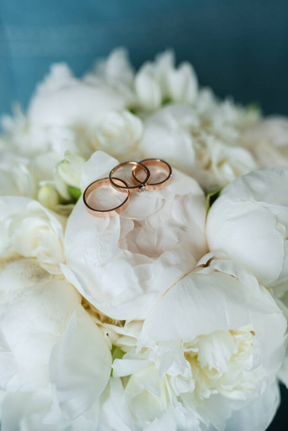 Gold wedding rings licked under the bark of a tree on a red wedding bouquet - Фото, изображение