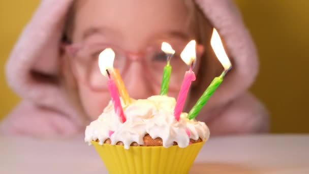 Szczęśliwa dziewczynka w różowym kombinezonie zdmuchnęła pięć świeczek na torcie urodzinowym na imprezie. Zbliż się do dziewczyny. Slow motion szczęśliwy urodzinowy baner wideo - Materiał filmowy, wideo