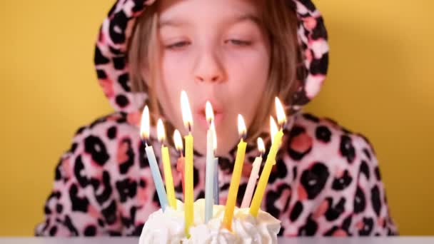 Fröhliches Teenie-Mädchen in Leoparden-Overalls bläst auf einer Party zehn bunte Kerzen auf Geburtstagskuchen aus. Nahaufnahme des Mädchengesichts. Video-Banner zum Geburtstag in Zeitlupe - Filmmaterial, Video
