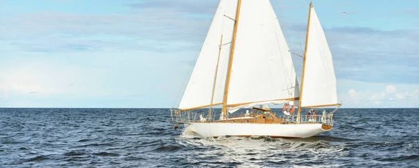 Oude dure vintage houten zeilboot (yawl) close-up, zeilen in een open zee. Prachtig wolkenlandschap. Kust van Maine, VS - Foto, afbeelding