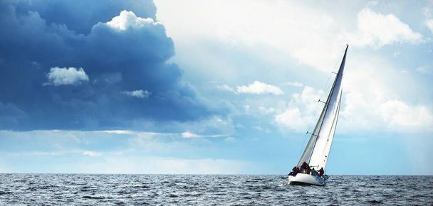 Purjehduspurjehdus regatta. Moderni purjevene kiiruhtaa aaltojen läpi. Dramaattinen taivas ennen ukkosta. Loistava pilvi. Pohjois-Saksa, Kiel - Valokuva, kuva