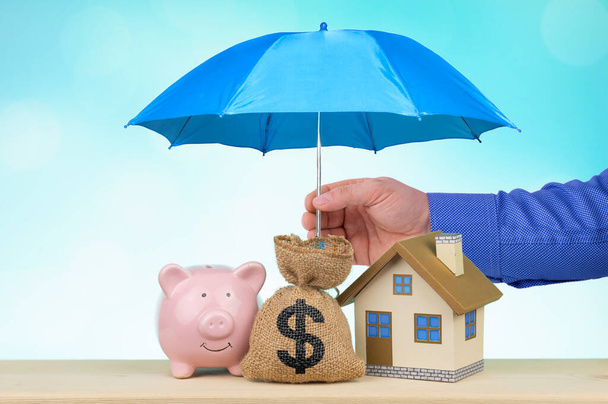 Blue umbrella protect home sack bag and piggy bank real estate and property protection or loan saving money concept. - Fotografie, Obrázek