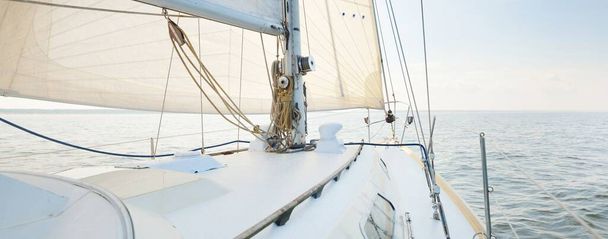 White yacht in an open sea on a clear day. A view from the deck to the bow, mast and sails, rigging equipment close-up. Summer Atlantic sailing near Spain and Africa - Photo, Image