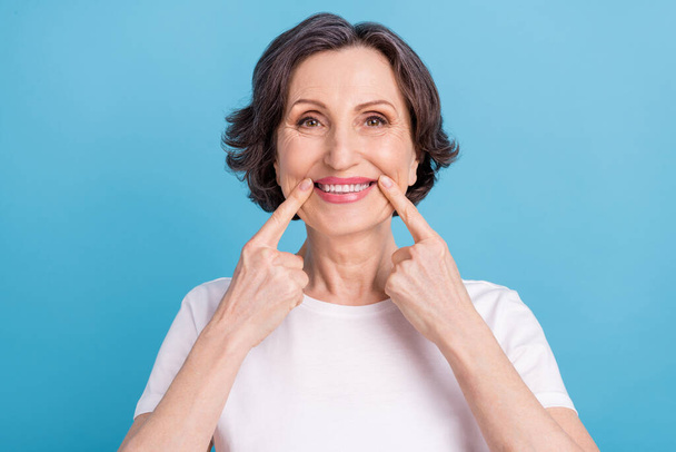 Photo portrait woman smiling showing finger pointing white teeth veneers isolated pastel blue color background - Foto, immagini