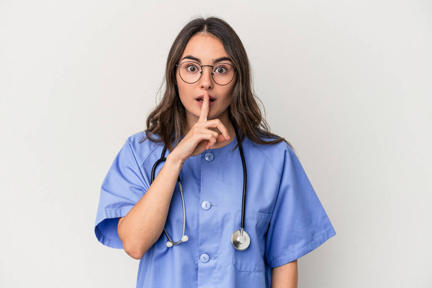 Young caucasian nurse woman isolated on white background keeping a secret or asking for silence. - Foto, imagen