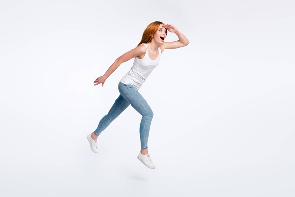 Full body photo of cheerful orange hairdo lady run look wear white top jeans isolated on bright color background - Foto, afbeelding