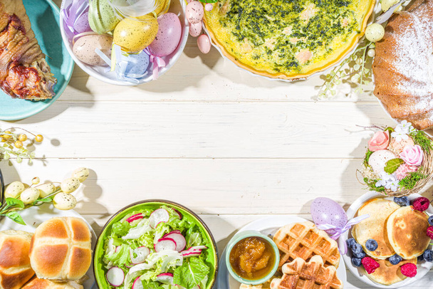 Cena festiva, almuerzo de Pascua. Platos tradicionales de Pascua en la mesa de la casa de la familia carne al horno, quiche, ensalada de primavera, magdalena, huevos de colores, bollos de cruz caliente - Foto, Imagen