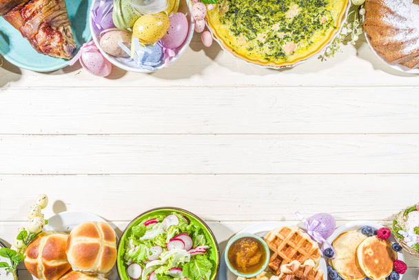 Festive dinner, Easter brunch. Traditional Easter dishes on family home table - baked meat, quiche, spring salad, muffin, colored eggs, hot cross buns - Photo, Image