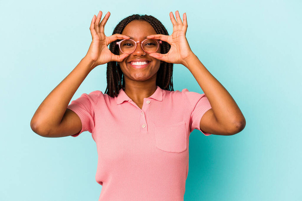 Young african american woman isolated on blue background  excited keeping ok gesture on eye. - Foto, afbeelding