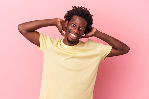 Young african american man isolated on pink background stretching arms, relaxed position. - 写真・画像