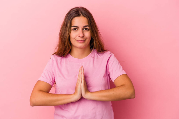 Young caucasian woman isolated on pink background  praying, showing devotion, religious person looking for divine inspiration. - Фото, зображення