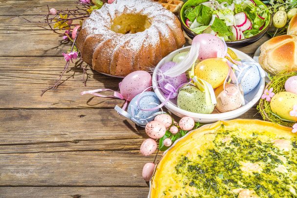 Festive dinner, Easter brunch. Traditional Easter dishes on family home table - baked meat, quiche, spring salad, muffin, colored eggs, hot cross buns - Photo, Image